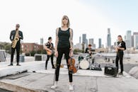 A Woman in Black Tank Top and Black Pants Holding a Violin