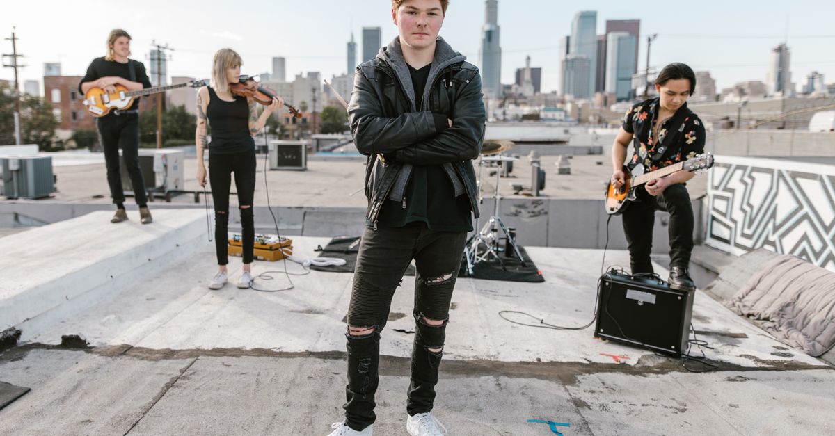 A teenager playing guitar on a rooftop at sunset, looking confident and inspired