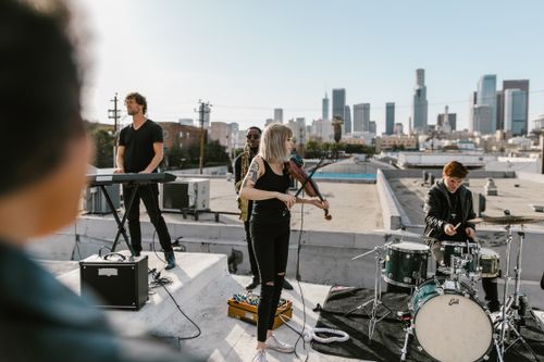 Free A vibrant band playing music on a rooftop with the city skyline in the background. Stock Photo