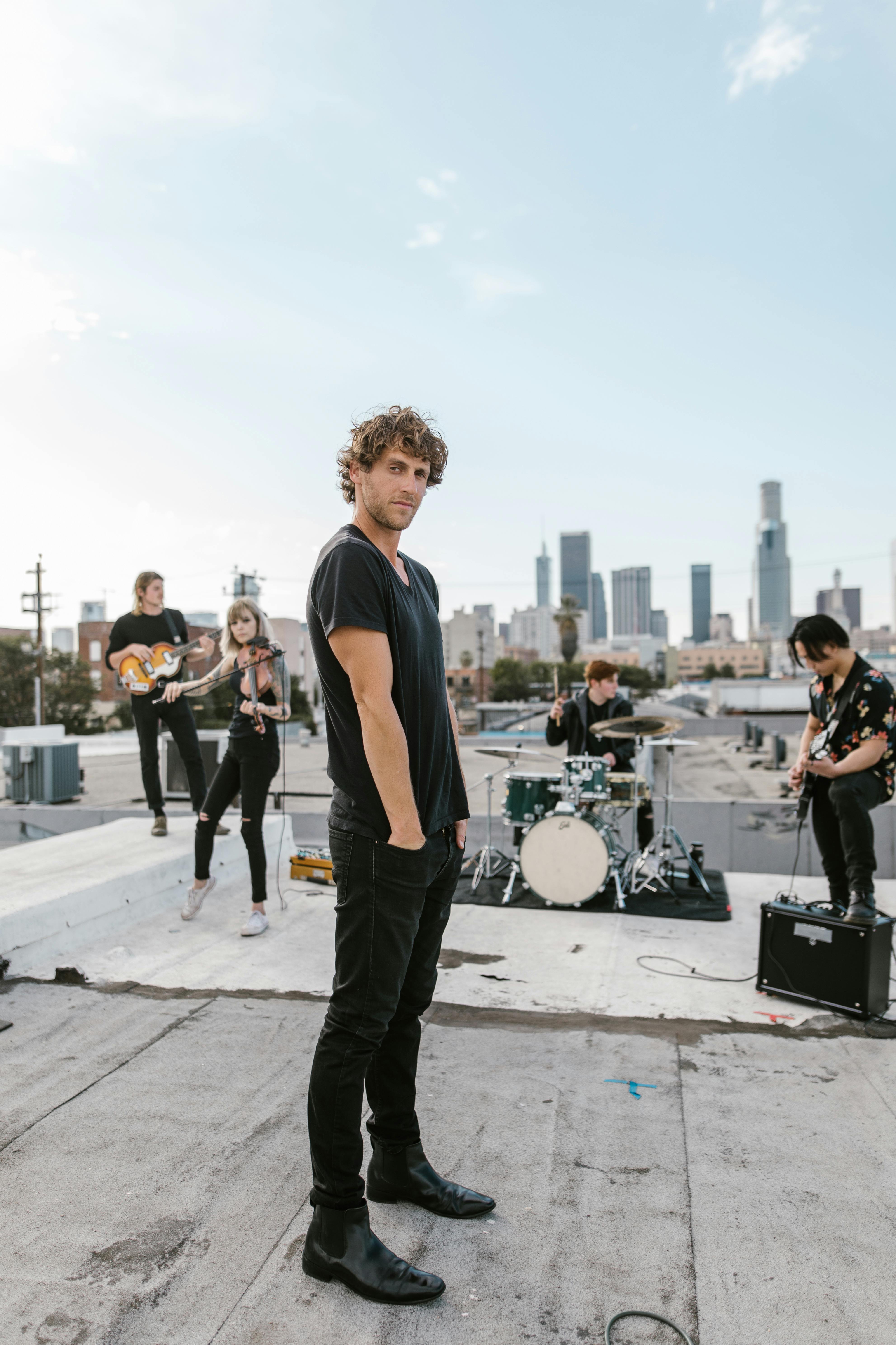 Man in Black Long Sleeve Shirt and Blue Denim Jeans Standing on Gray Concrete Floor during