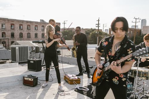 Free A diverse group of musicians performing on a rooftop with saxophone, guitar, and violin. Stock Photo