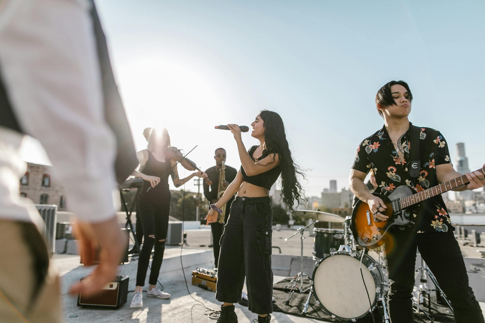 A diverse band performs outdoors at sunset, showcasing various musical instruments and talent.