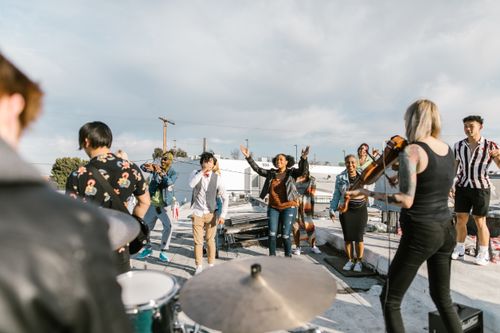 Free A lively rooftop band performance with musicians and audience enjoying a sunny day. Stock Photo