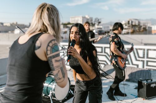 Free Vibrant musicians performing on a rooftop with guitars and microphones, capturing live music energy. Stock Photo