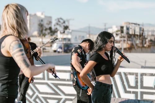 Free A lively outdoor band performance featuring a female vocalist singing passionately with musicians. Stock Photo