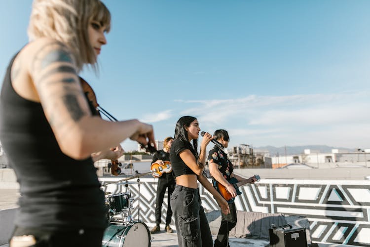 A Band With A Woman Vocalist Singing Under Blue Sky