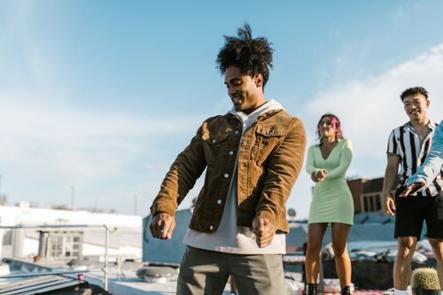 Free Group of young adults enjoying a rooftop party, dancing under the clear sky. Stock Photo