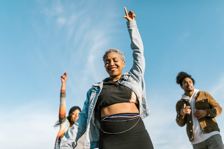 A Woman In A Denim Jacket Pointing To The Blue Sky