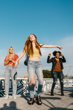 Group of diverse young women enjoying dance together outdoors on a sunny day.