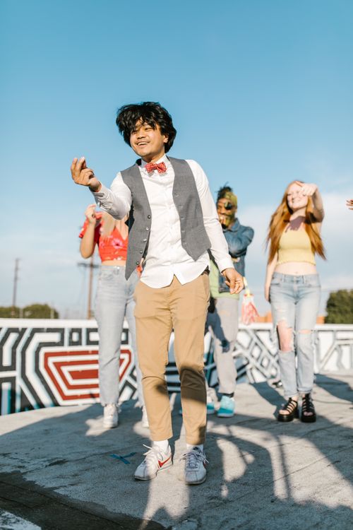 Free Youthful friends expressing joy and dance moves in urban setting, vibrant street fashion. Stock Photo