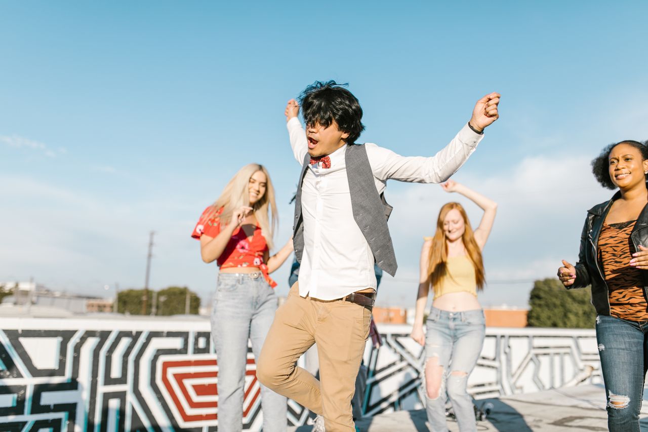young adults enjoying a vibrant rooftop dance party under a clear blue