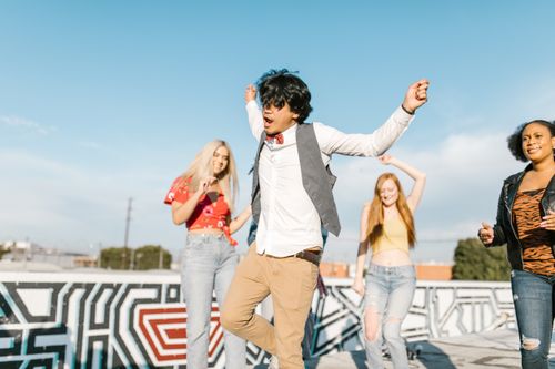 Free Young adults enjoying a vibrant rooftop dance party under a clear blue sky. Stock Photo