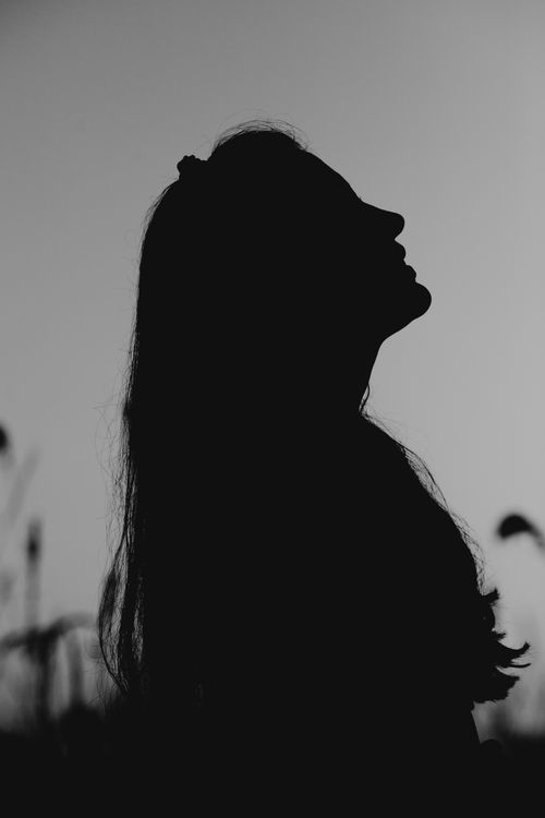 Free Black and white silhouette of a woman looking upwards outdoors. Stock Photo
