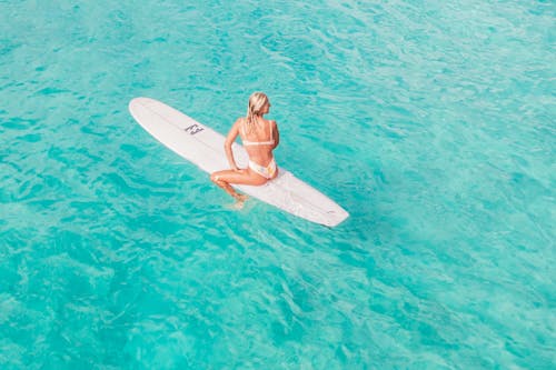 A Woman in Bikini Sitting on a Surfboard