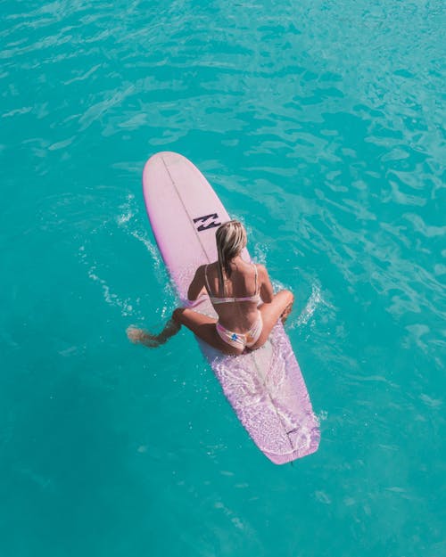 A Woman in Bikini Sitting on a Surfboard