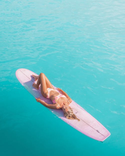 A Woman in Bikini Lying on a Surfboard