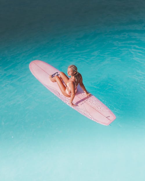 A Woman in Bikini Sitting on a Surfboard