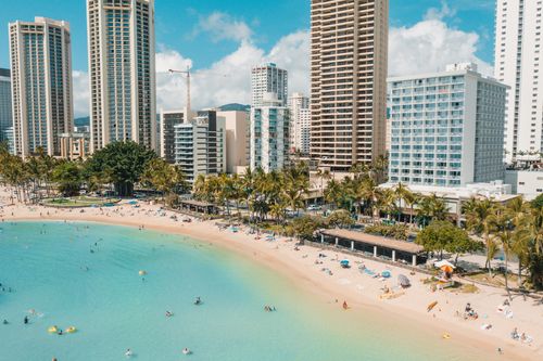 Free Aerial shot of a bustling city beach with high-rise buildings and vibrant beachgoers. Stock Photo