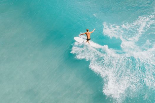 Dynamic aerial view of a surfer skillfully navigating a wave on a bright sunny day.