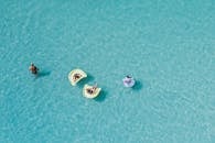 空中拍摄的人们在美丽的蓝色水上的浮管上放松，享受休闲时光