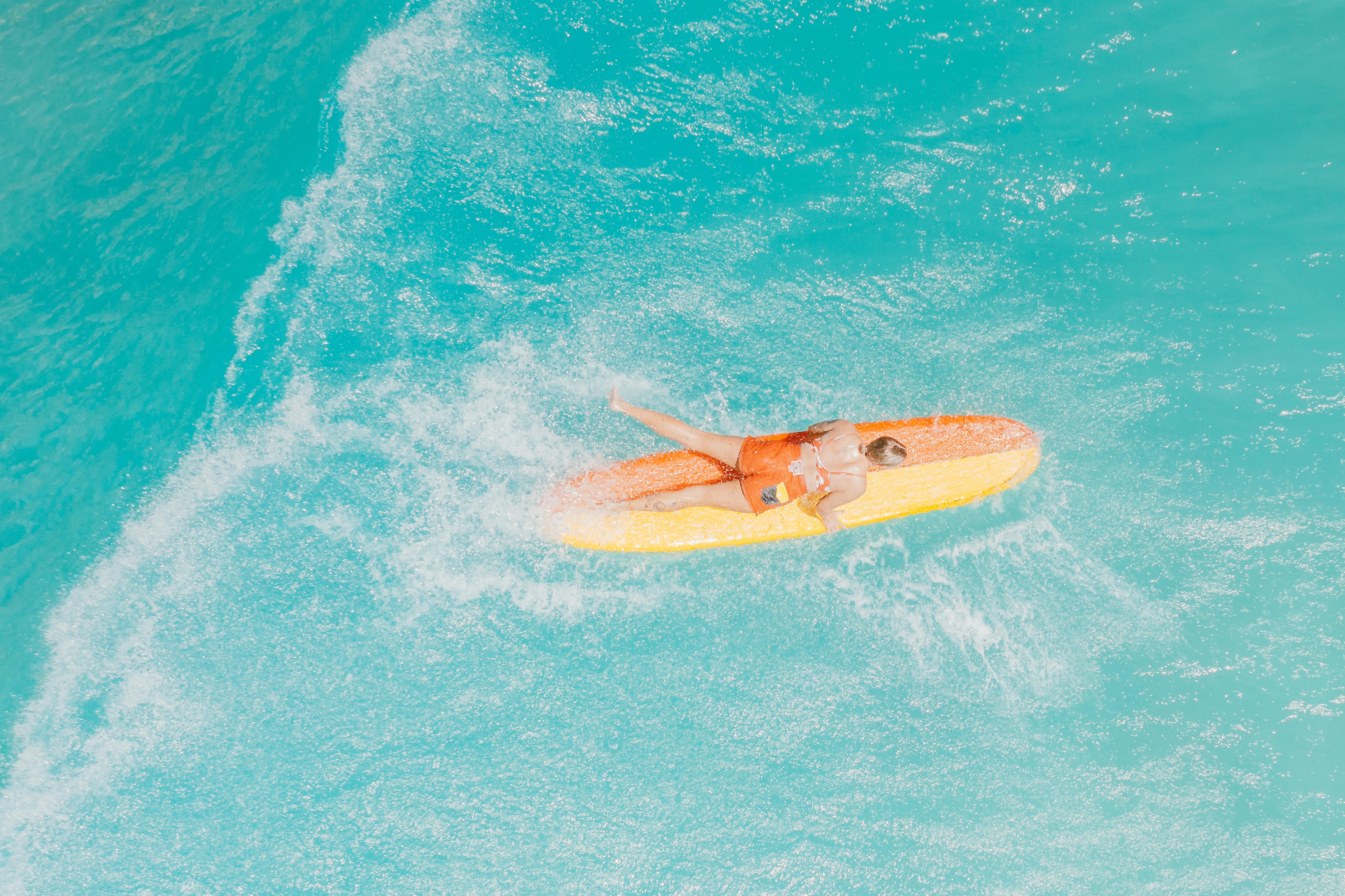一个女人在充满活力的蓝色海洋上冲浪的航拍，捕捉了夏季娱乐的精髓