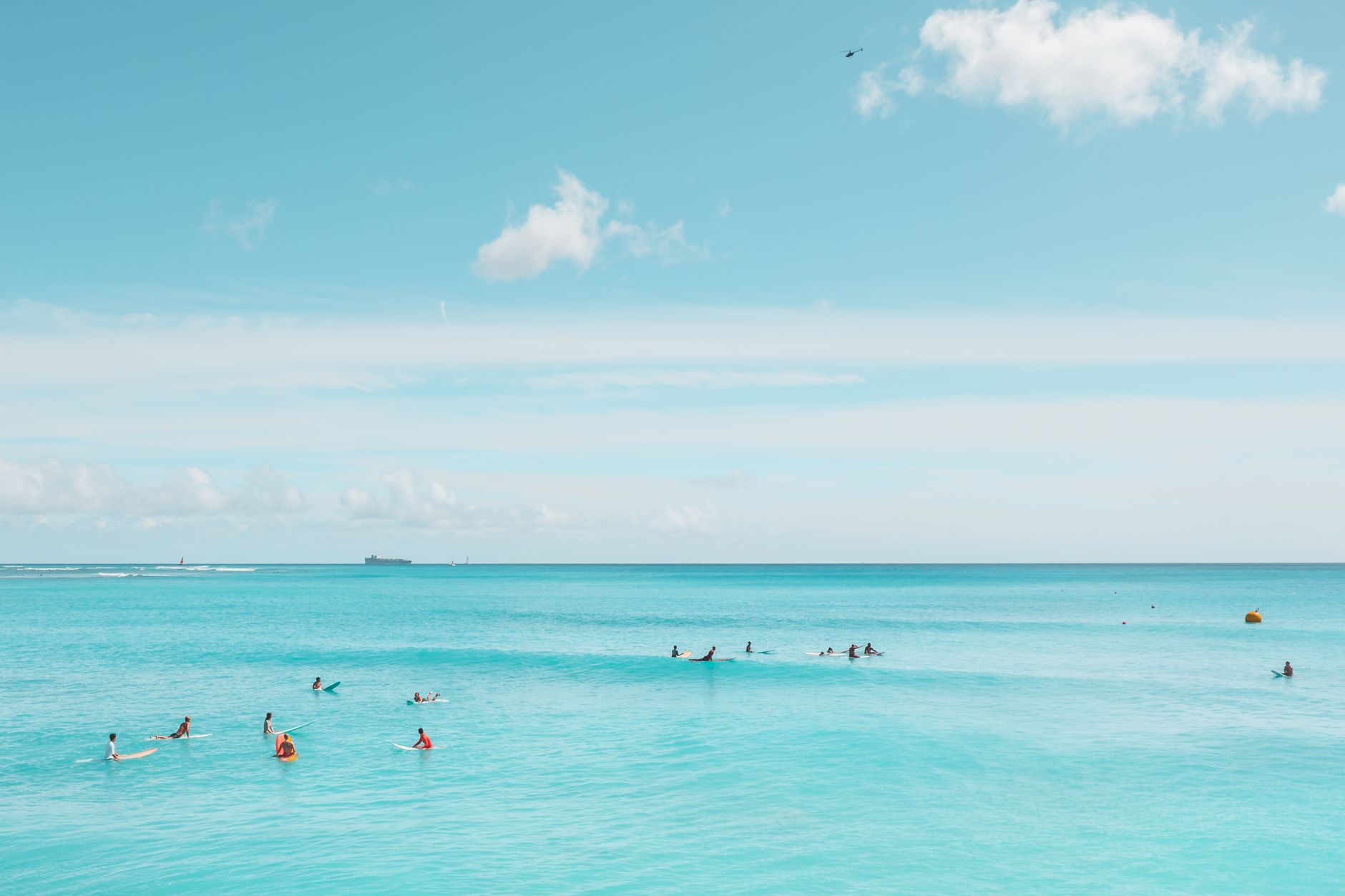 A scenic view of surfers enjoying a sunny day on the turquoise waters of a tropical beach.