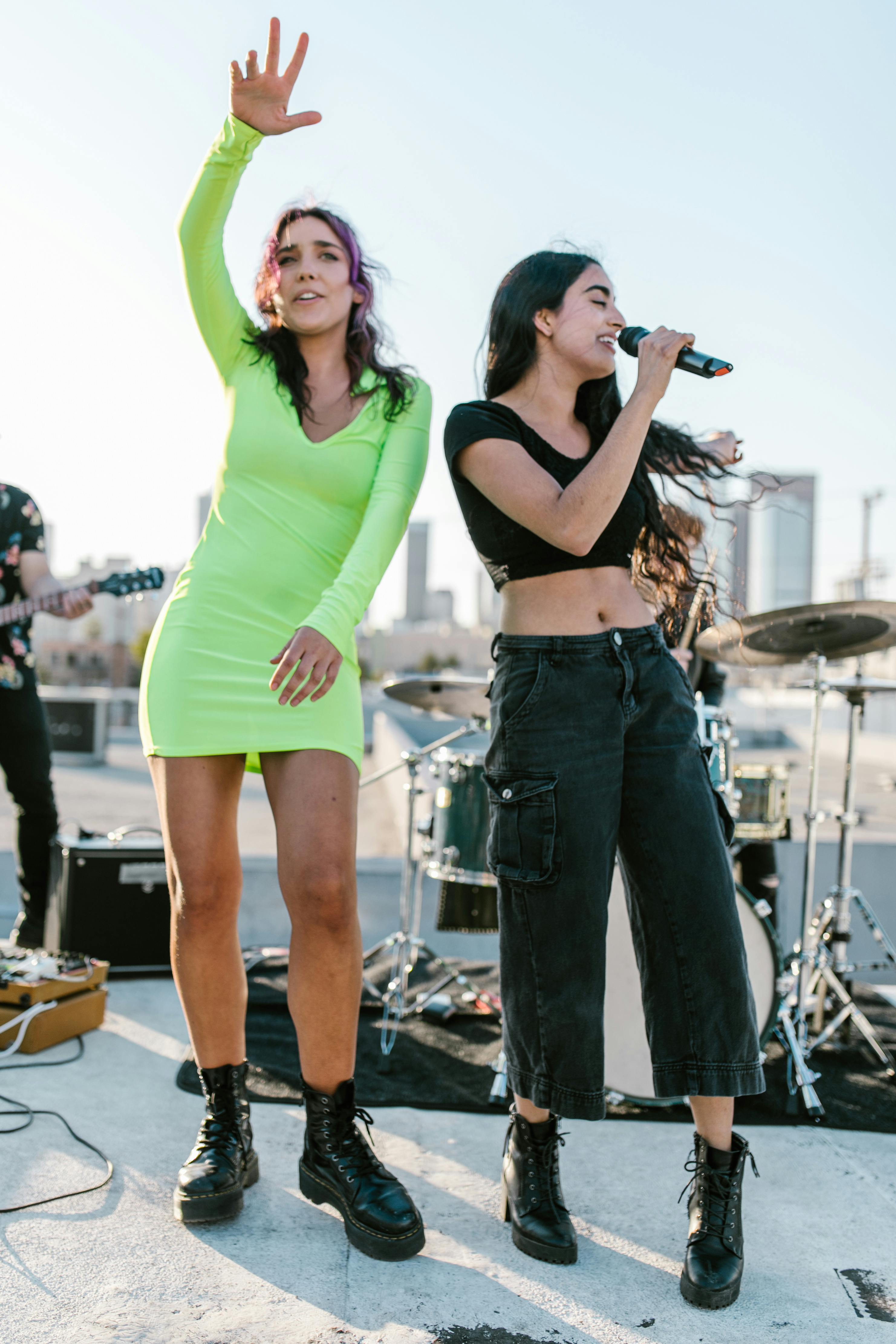 Woman in Green Tank Top and Blue Denim Shorts Holding Microphone