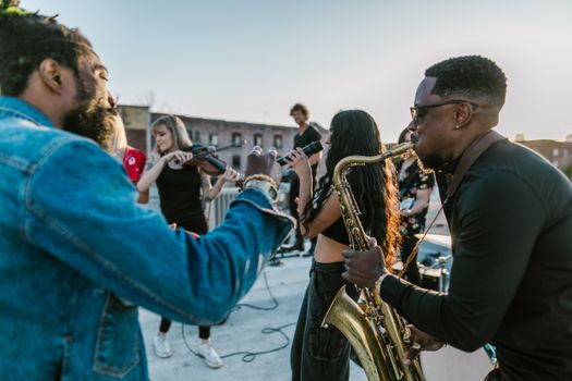 A vibrant rooftop concert showcasing a diverse group of musicians playing various instruments at sunset.