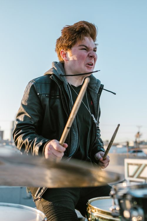 Free Young male drummer passionately playing drums outdoors, showcasing intense facial expression. Stock Photo