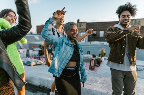Free A joyful rooftop party with diverse friends dancing and celebrating under a clear sky. Stock Photo