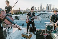 Man in Black and White Floral Button Up Shirt Playing Electric Guitar