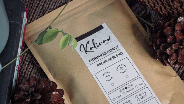 Aesthetic brown coffee pouch surrounded by pine cones and leaves, perfect for rustic themes.