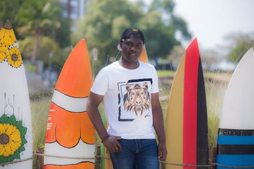 Smiling Man Standing Beside the Surfboards