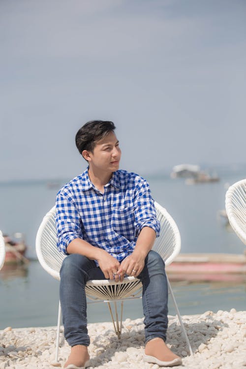 Man in a Checkered Shirt Sitting on a White Chair