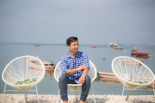 Man in Blue Plaid Shirt Sitting on Wicker Chair