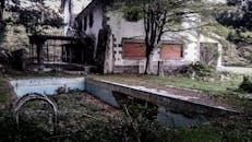 一座破旧的房子和杂草丛生的游泳池被森林环绕，象征着腐朽