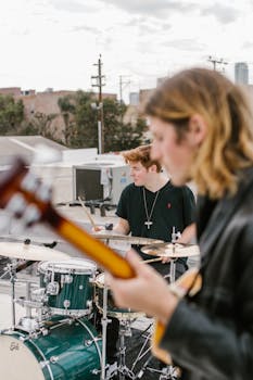Energetic rooftop band performance featuring guitarist and drummer.