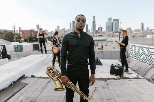 A Man in Black Long Sleeves Holding Saxophone
