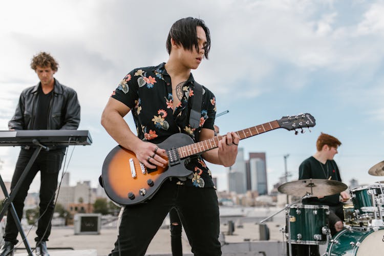 Man In Black Floral Shirt Playing Electric Guitar In Music Band On The Rooftop