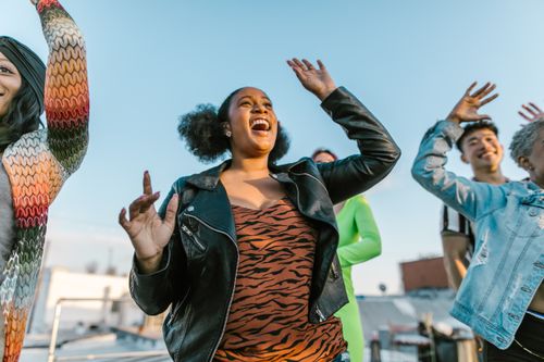 Free A diverse group of friends dancing and having fun on a rooftop during the day. Stock Photo