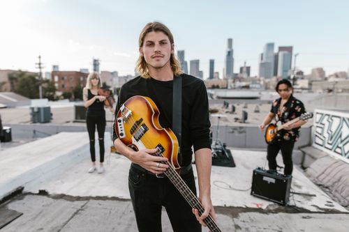 Free Musicians playing on a rooftop with cityscape in the background, showcasing urban music culture. Stock Photo