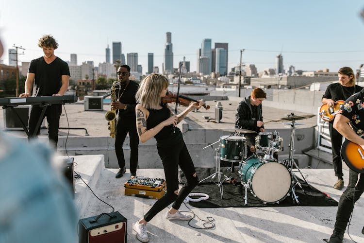 Woman Playing Violin On The Rooftop With Music Band