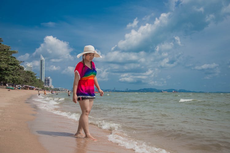 Girl In Hat And Bright Top Walking On The Beach