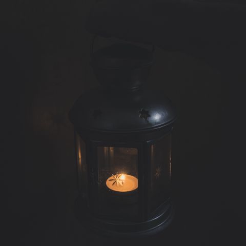 A single candle lantern glowing in the dark — Matej on Pexels