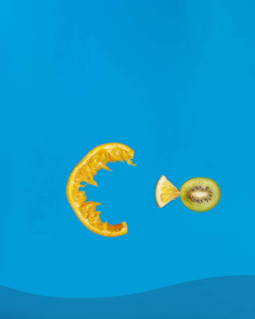 A Mouth and Fish made of Slices of Tropical Fruits on Blue Background