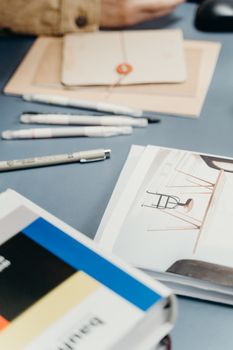 A well-organized desk featuring notebooks, pens, and a design book for creative projects.