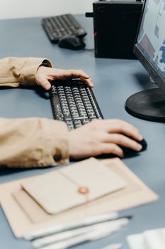 Hands typing on a keyboard at a workstation with a blurred background.