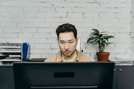 An office worker concentrating on tasks at his modern desk in a contemporary setting.