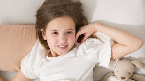 Free A Girl in White Shirt Lying on the Bed Stock Photo