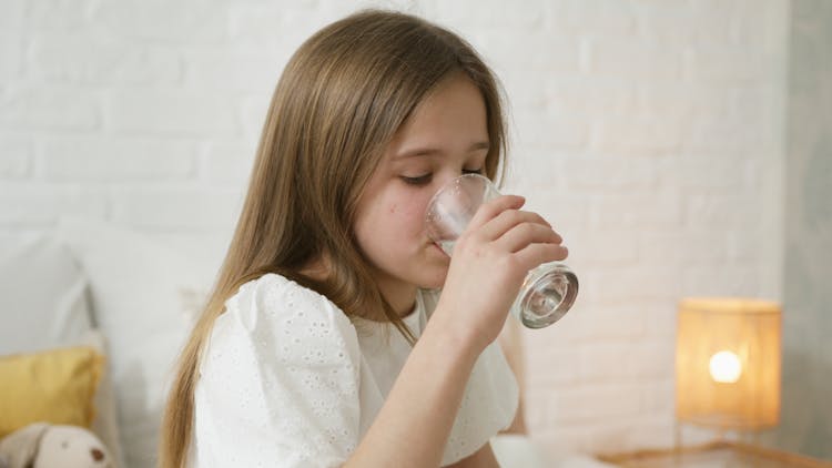 A Girl Drinking A Glass Of Water